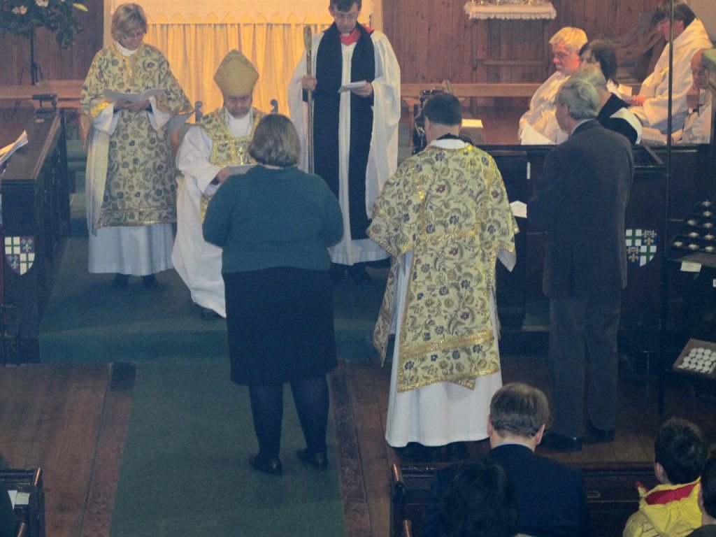 The Vestry Secretary, Bridget Campbell,  (left) and Treasurer, Michael Paulson-Ellis, (right) present Canon Allan Maclean to the Bishop of Edinburgh at his Institution on St Vincent's Day, 22 January 2015